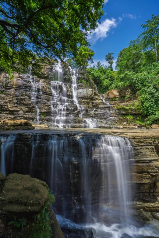 a waterfall with green vegetation on top