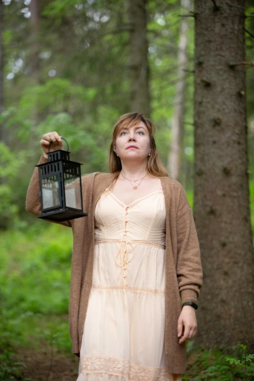 the woman in the dress is holding up a lantern