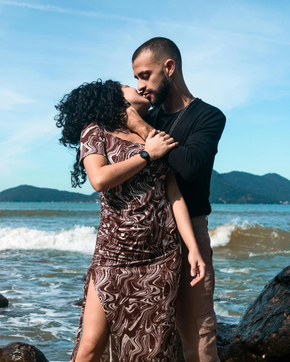 the man and woman are kissing next to the ocean