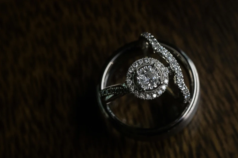 a wedding ring sits in the middle of a wood surface