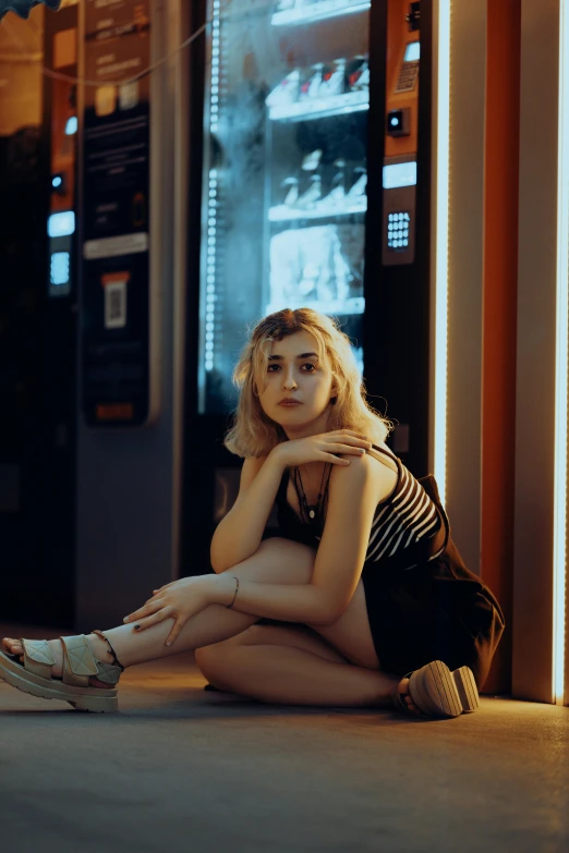 a woman sitting on the ground outside a vending machine