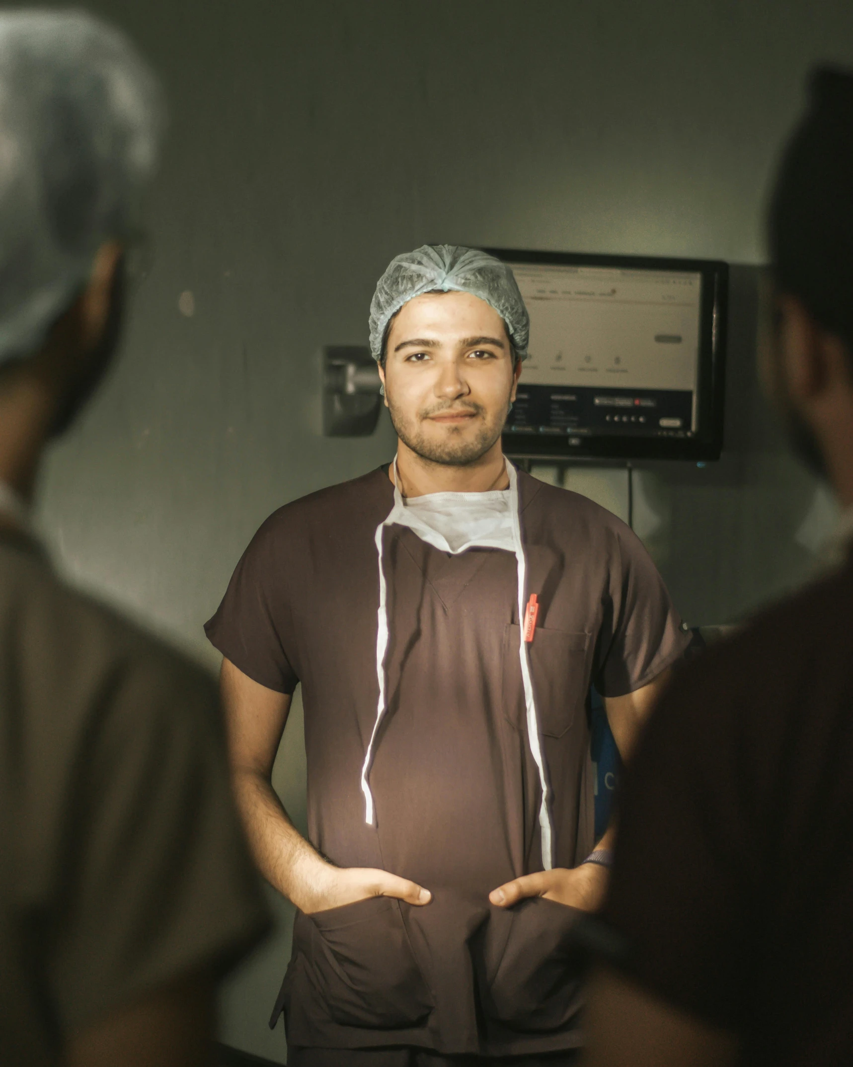 a man wearing scrubs standing with his hands behind his back