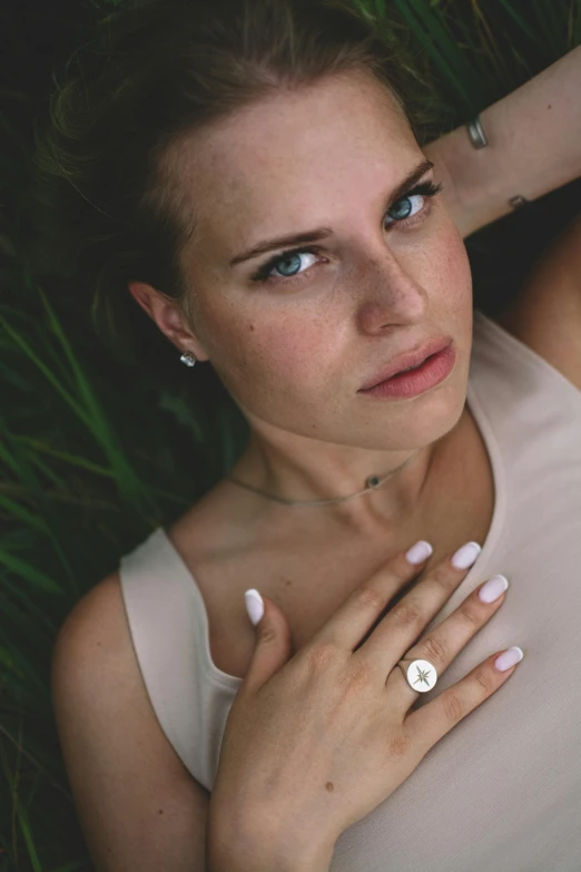 woman in tank top lying on grass with ring