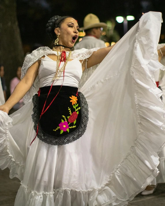 woman in a white dress singing while holding her long white skirt