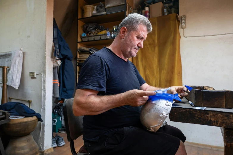 a man that is sitting down with a pair of scissors