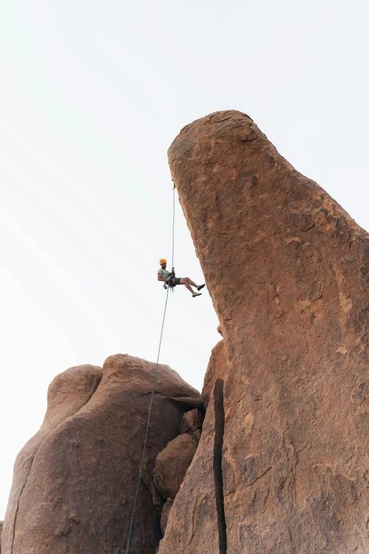 a man holding onto a rope as he climbs up a large rock