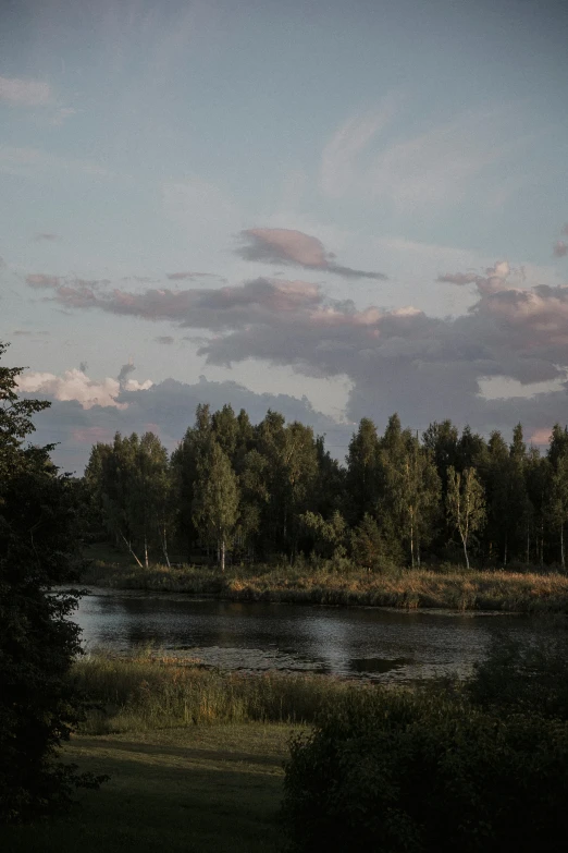 a cloudy sky over a lake with some trees around it