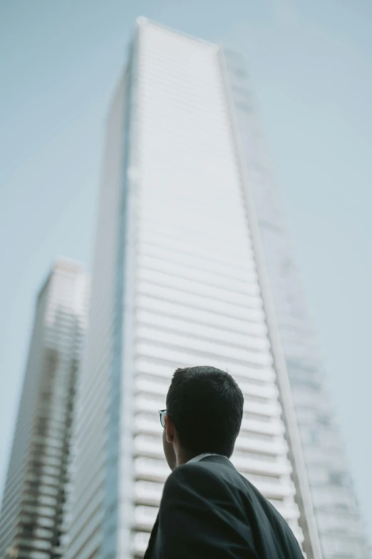 a man looking up at the sky in front of tall buildings