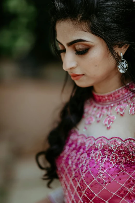 a woman with dark skin and pink dress, holding her hand behind her neck