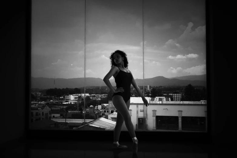 a woman wearing a bodysuit stands on the roof of a building