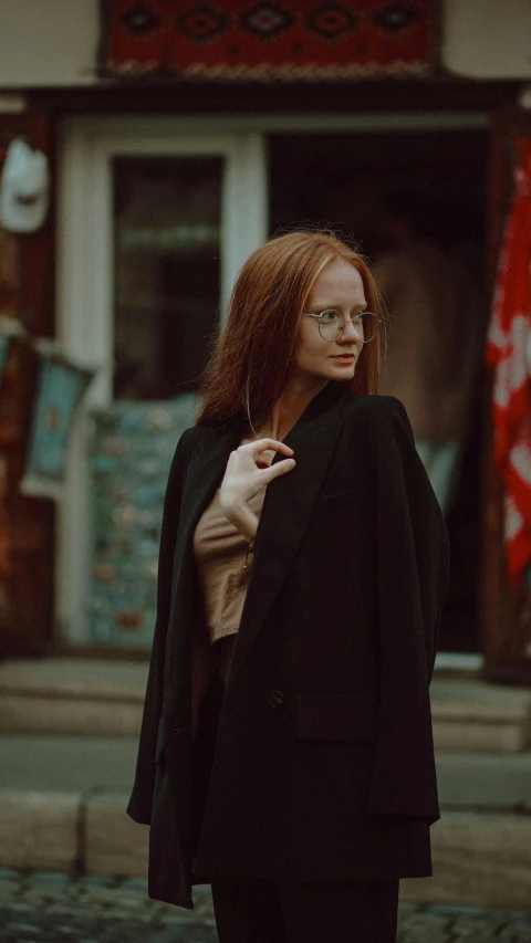 the woman in glasses stands near a building