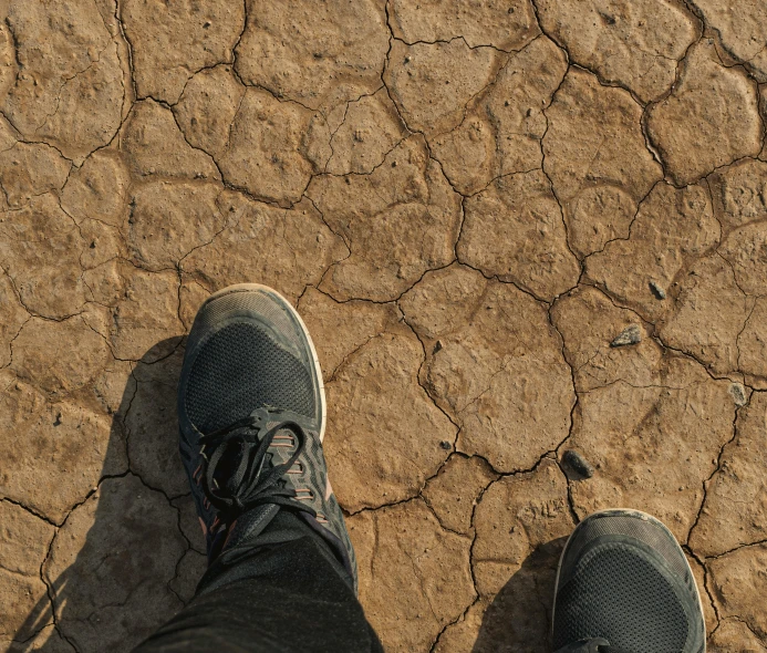 feet in sneakers on dirt ground with s