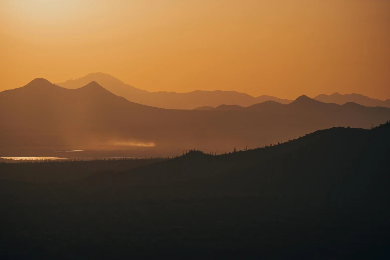 the sun rises over mountains on the horizon