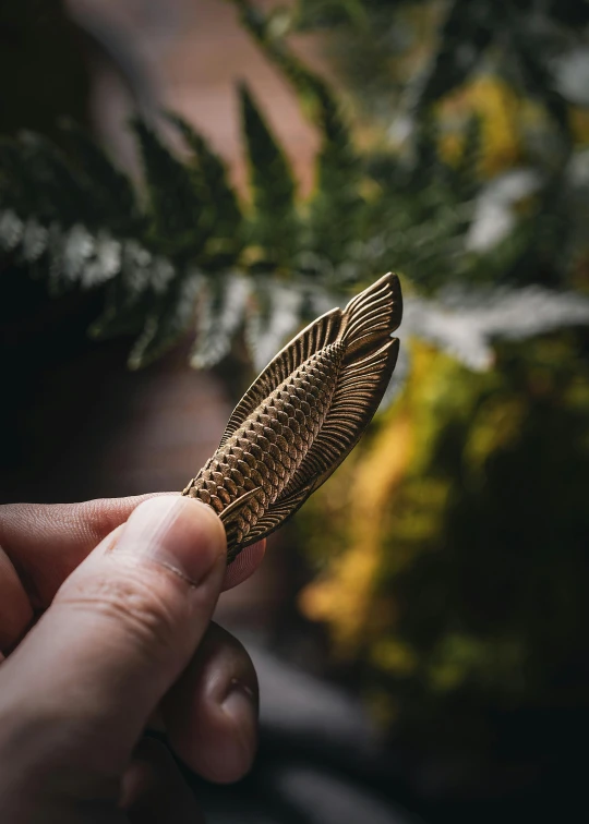 a person holding a small decorative object that looks like a fern