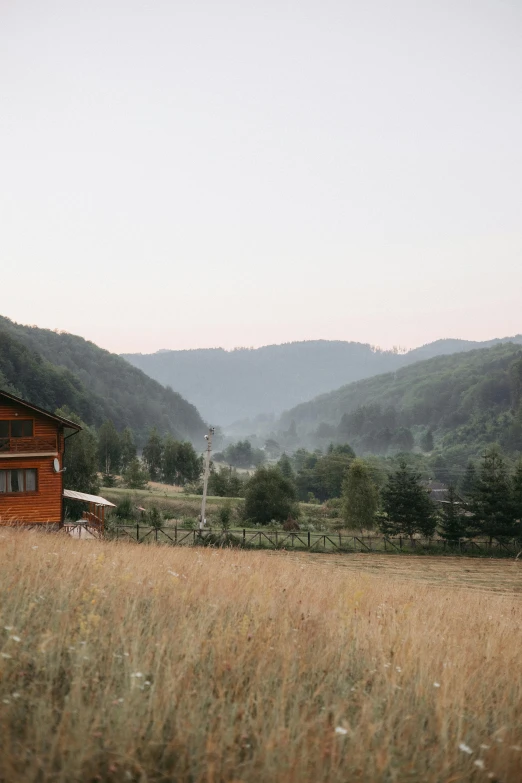 a house sitting in a field with mountains in the background