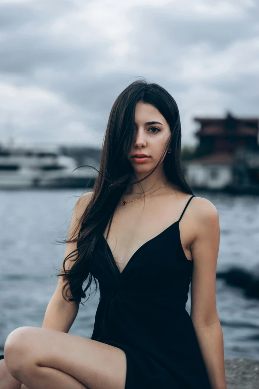 a beautiful young lady is sitting next to a body of water