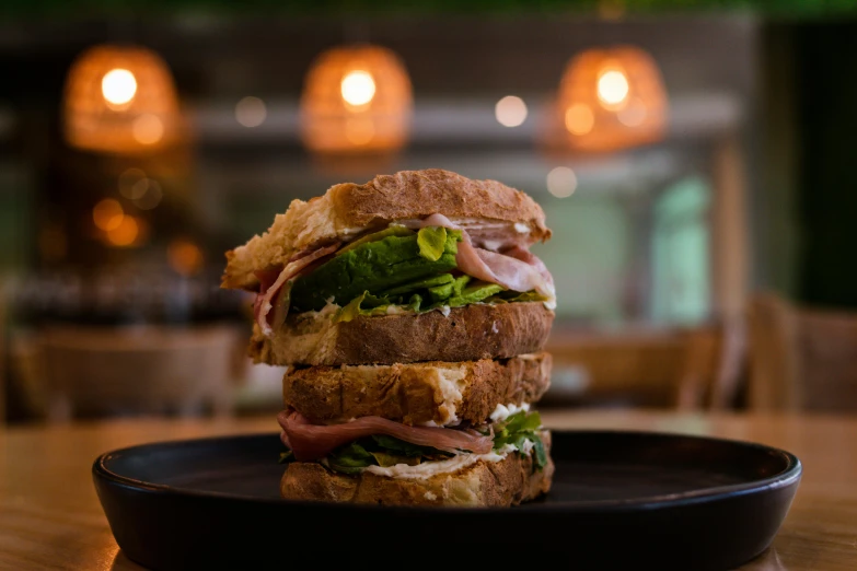 a sandwich sits on a plate in front of some candles