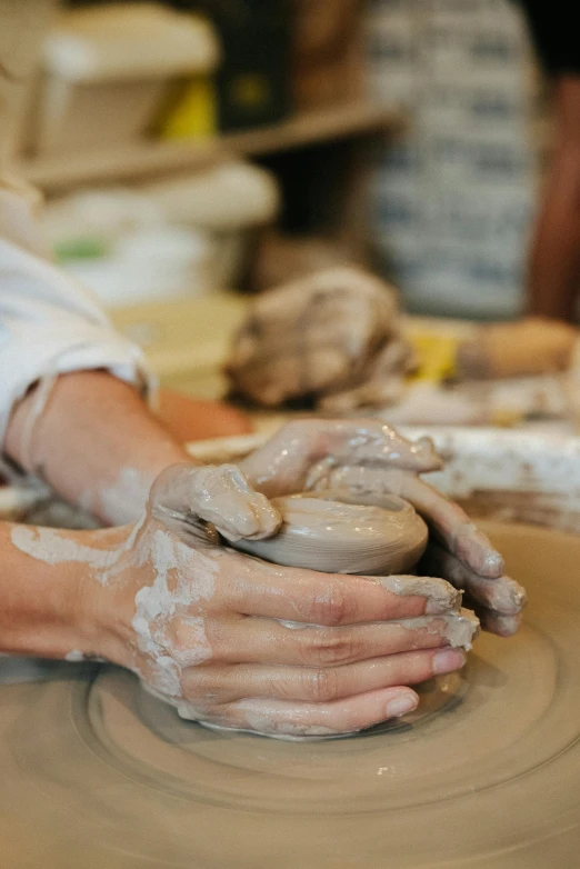 a potter at work casting a clay pot onto a wheel