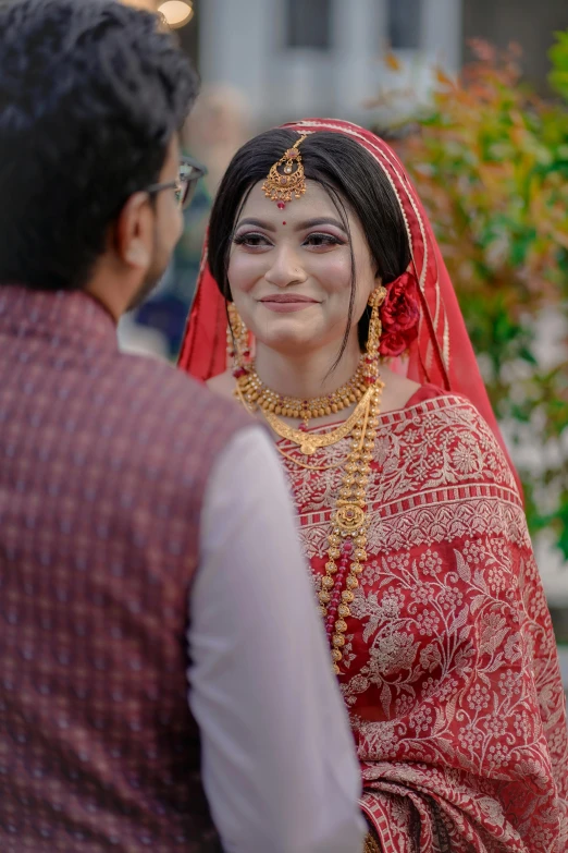 bride dressed in red and smiling with her groom in background