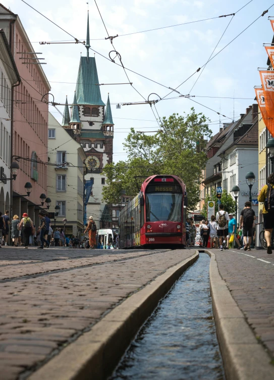 the red bus is going down the street near the buildings