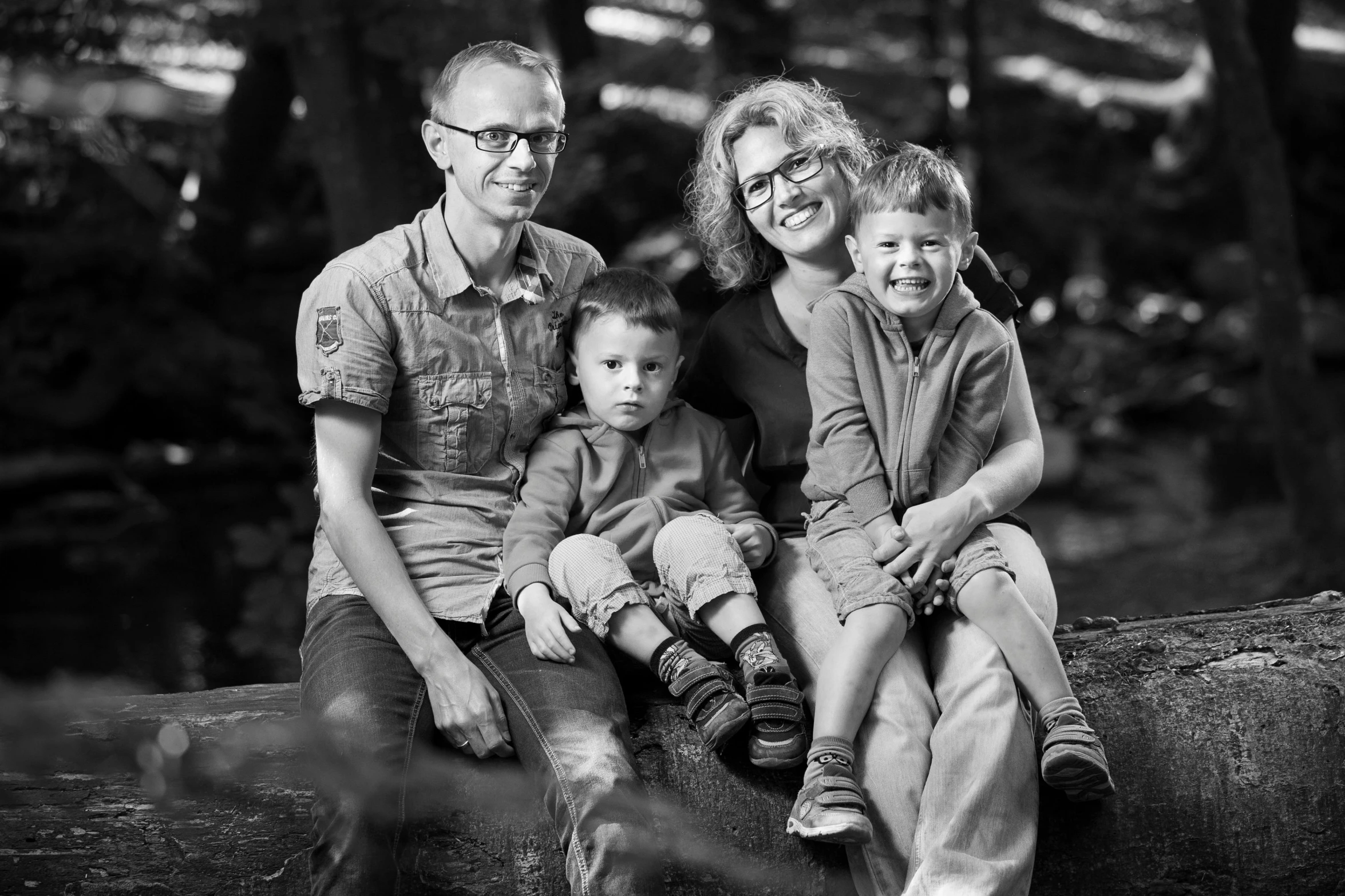 a black and white po of three people with two children on top of a log