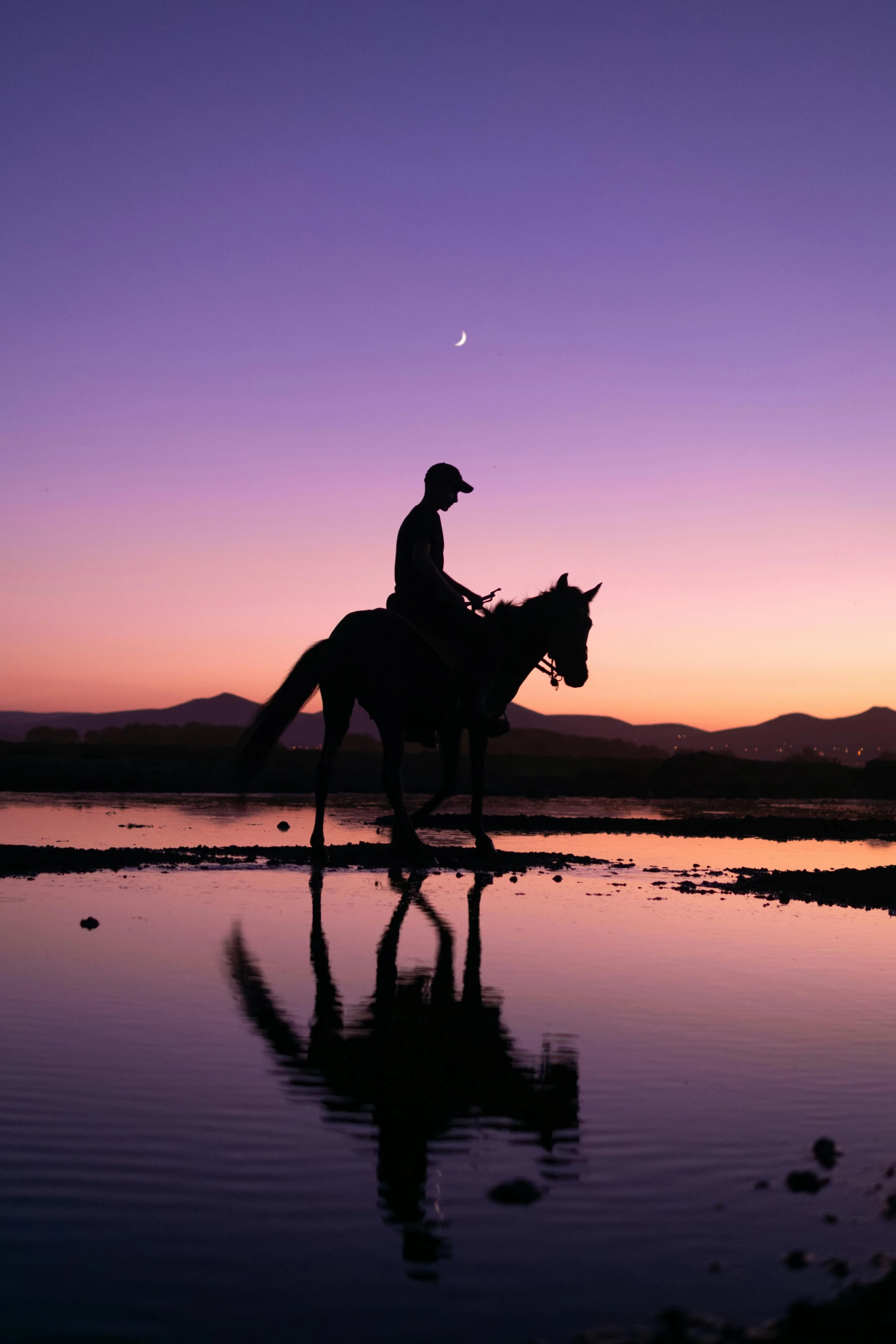 a man on top of a horse that is walking in some water