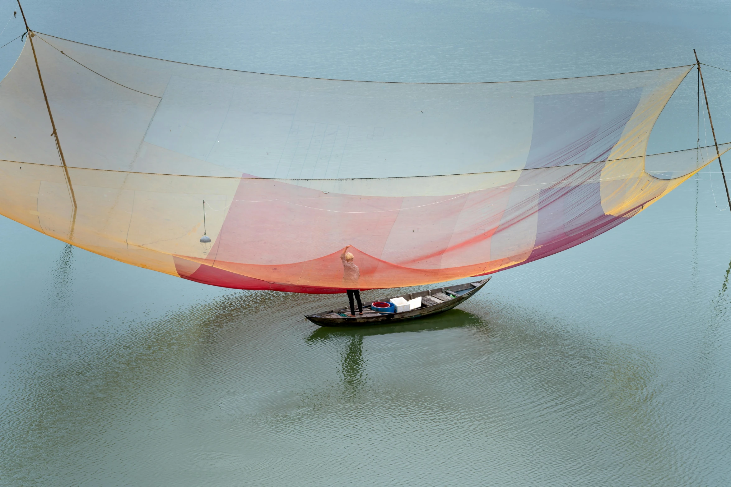 two people standing on a small sail boat on the river