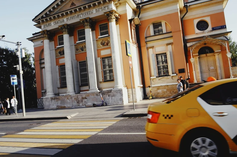 the yellow taxi is parked next to an old building