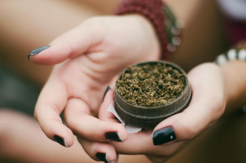 someone holding a small jar with leaves inside