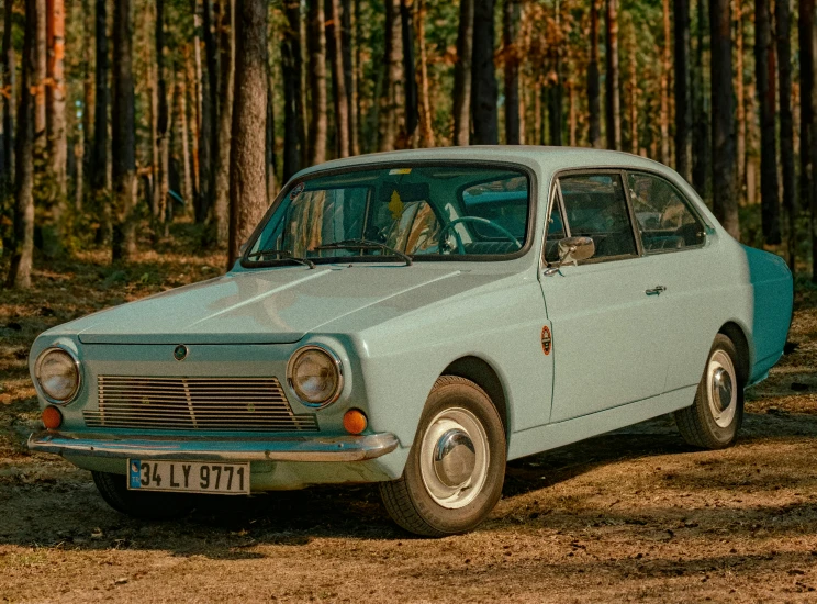 a light green car is sitting in a wooded area