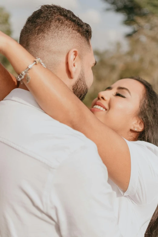 a beautiful young woman hugging a man who is holding her arms up