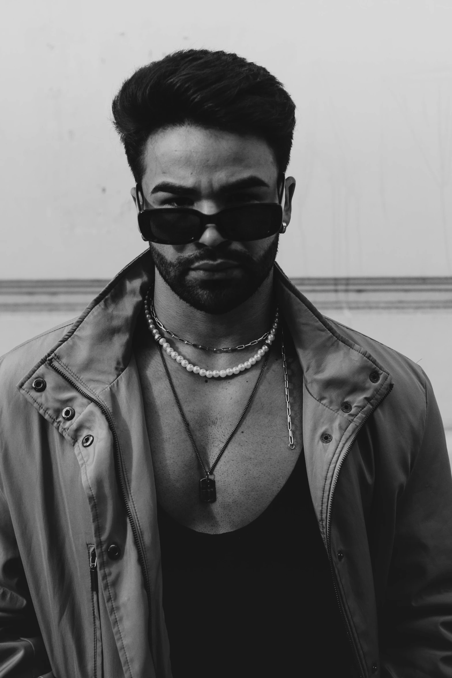 black and white pograph of a man wearing black sunglasses and necklace