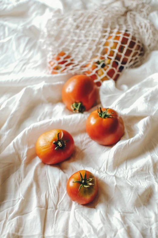 small tomatoes lie in an intricate pattern on a white sheet