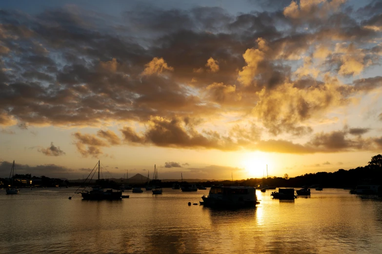 many small boats on the water with clouds in the sky