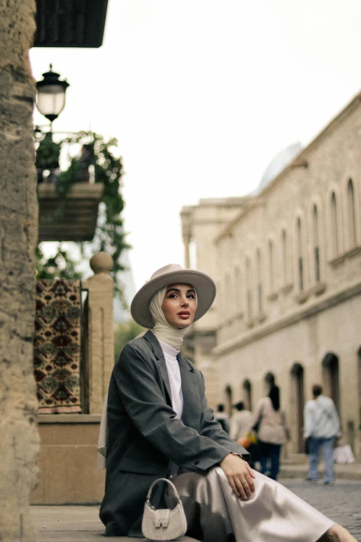 a young woman sitting on the ground in a hat