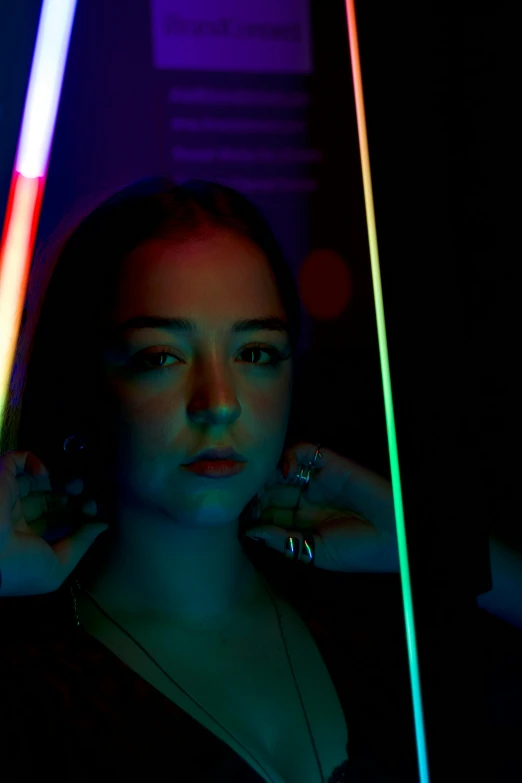 a woman standing next to three neon colored lights
