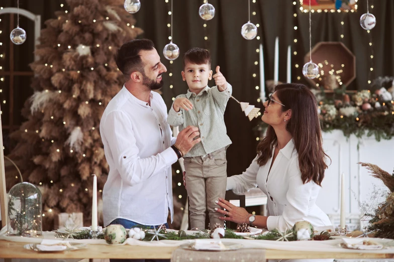 a man and a woman holding a little boy near a christmas tree