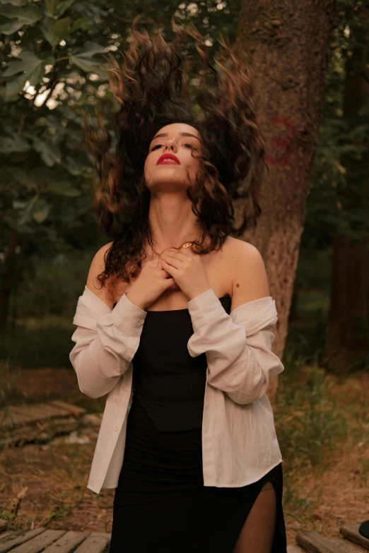 a girl standing next to a tree in a forest