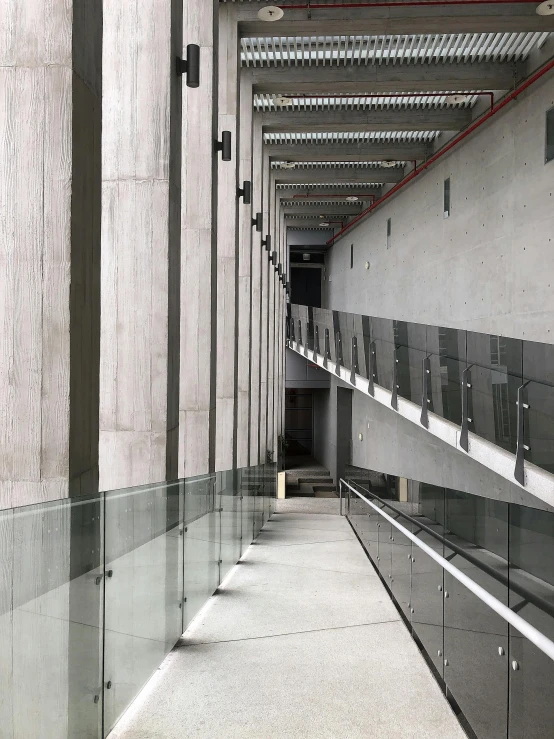 an empty lobby of an office building with lots of grey walls and metal railings