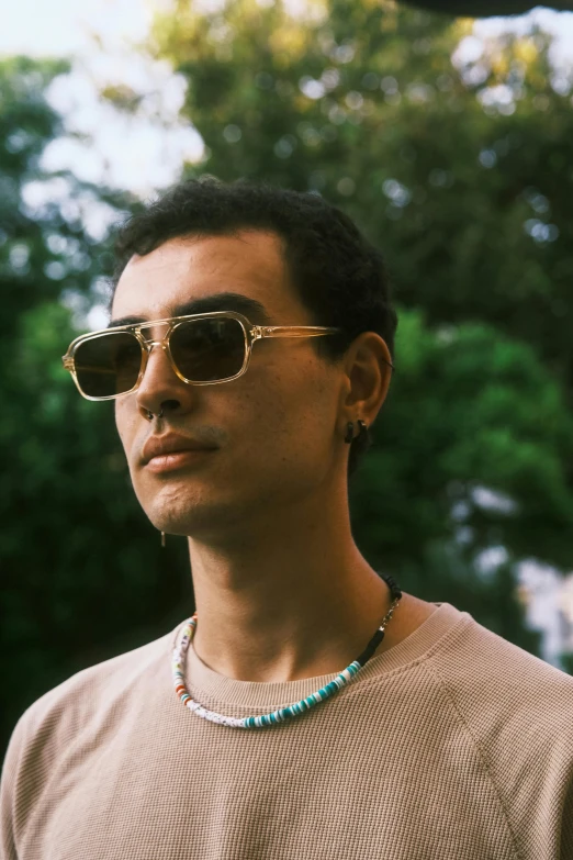a man wearing sunglasses, a shirt and necklace