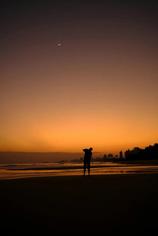 the silhouette of two people on a beach, at sunset