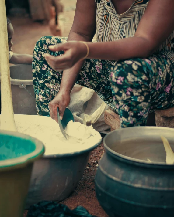 a woman is mixing out cream in two large containers