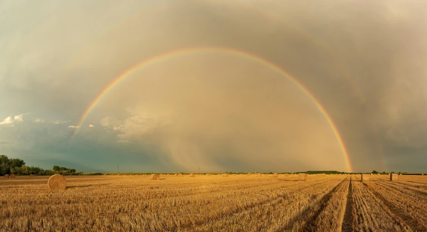 double rainbow with blue sky over a brown field