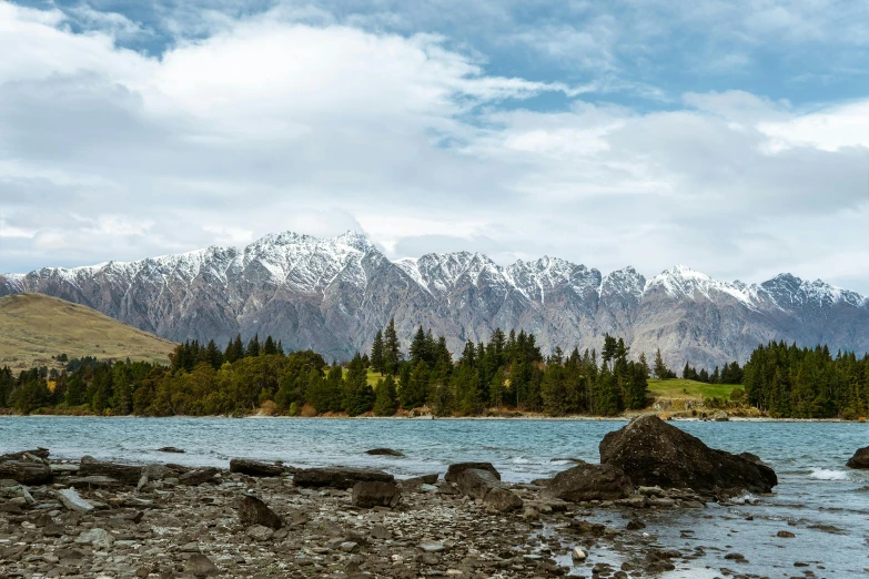 a small island in the middle of a lake with snow capped mountains in the distance