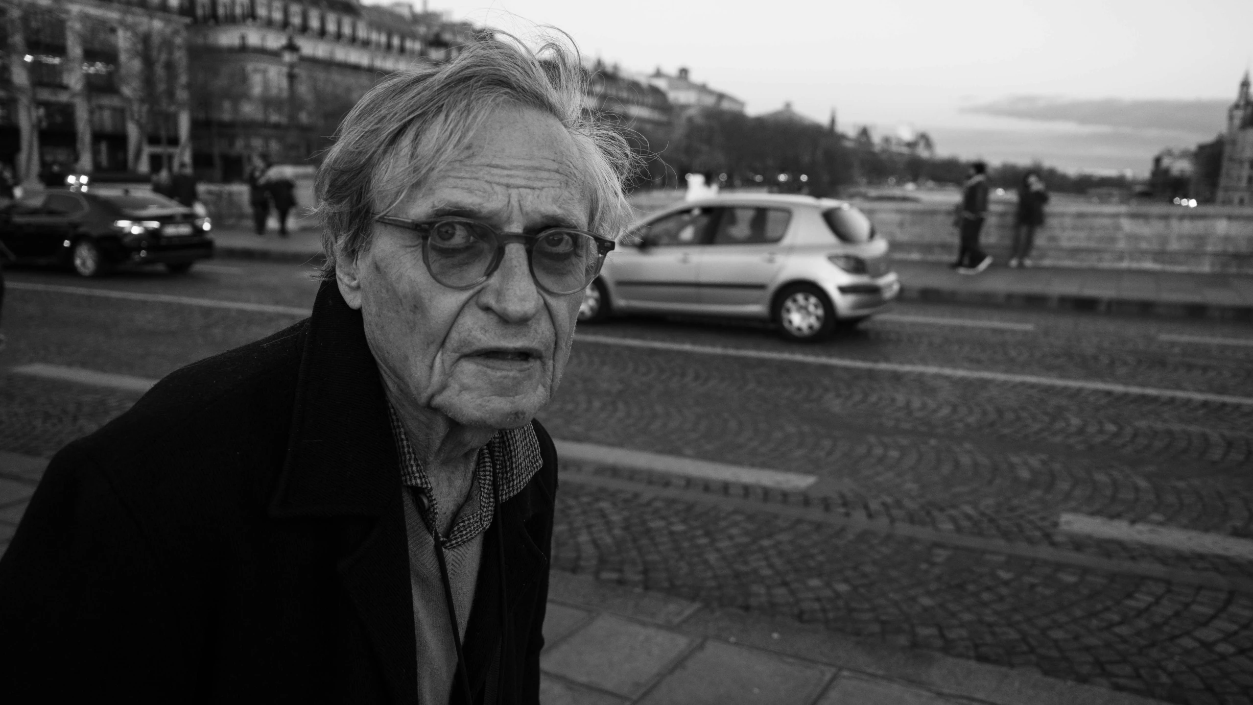 the older man is walking in the sidewalk of a town