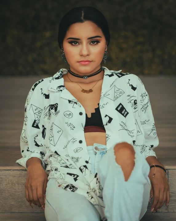 a young woman sitting on the ground and wearing a jacket