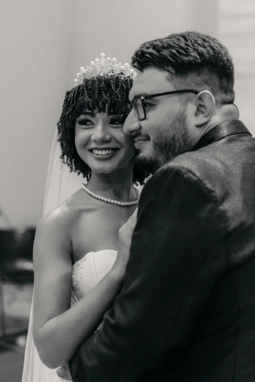 a smiling bride is hugging her groom in front of her