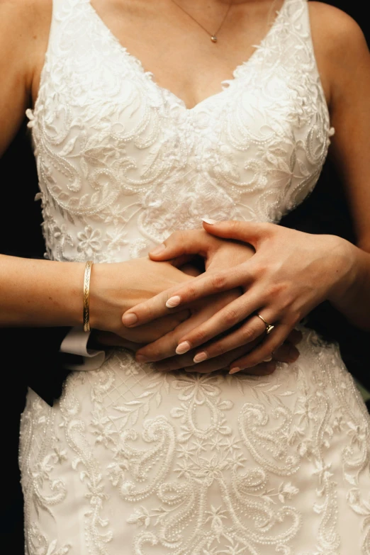 a close up of a bride's hands wrapped around her dress