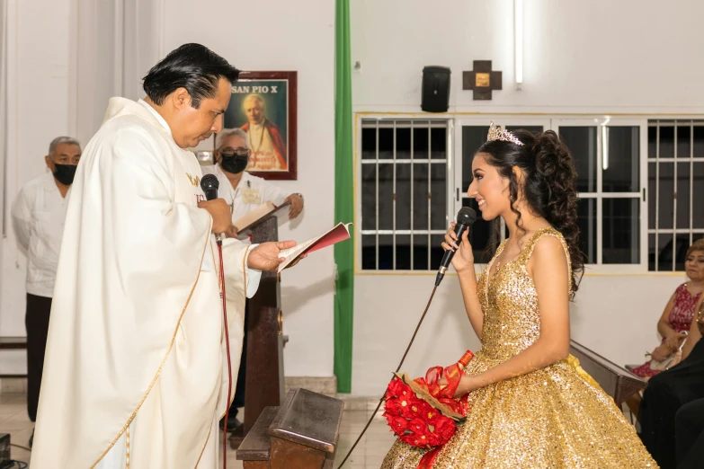 a little girl in a golden dress is speaking to the priest