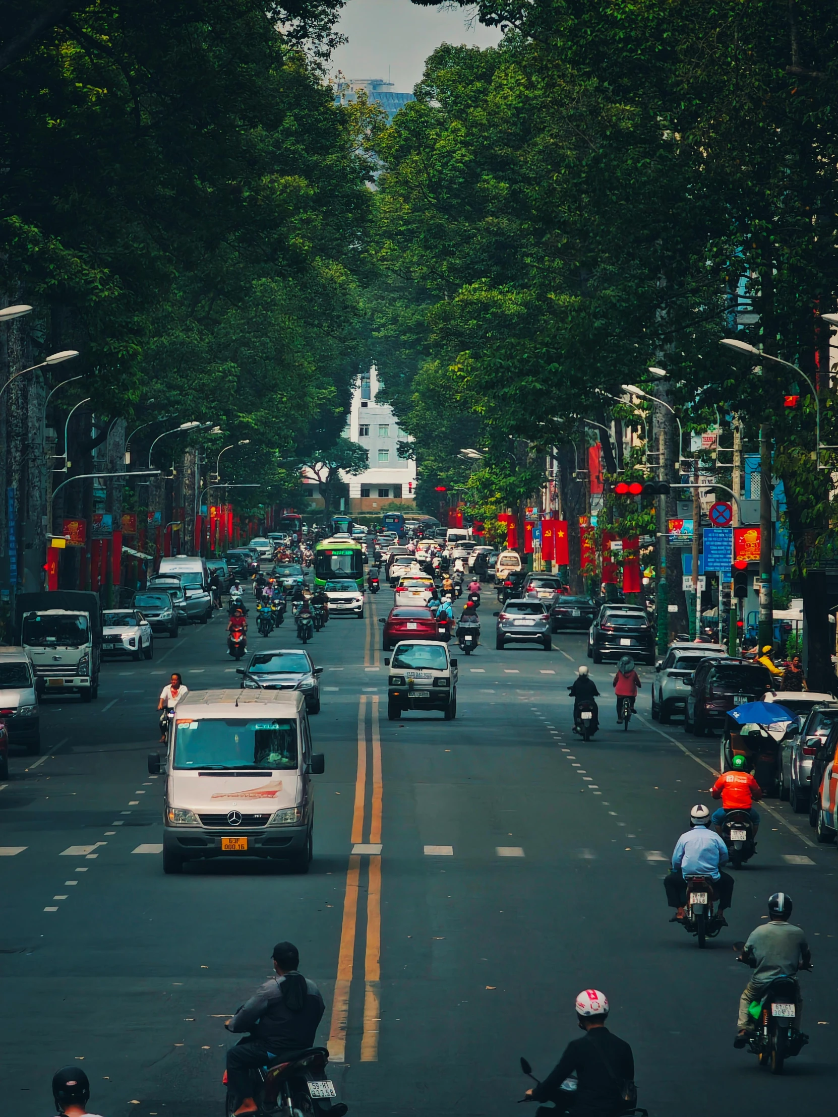 cars and motorbikes in the street with a city view